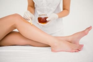 therapist-waxing-womans-leg-at-spa-cente